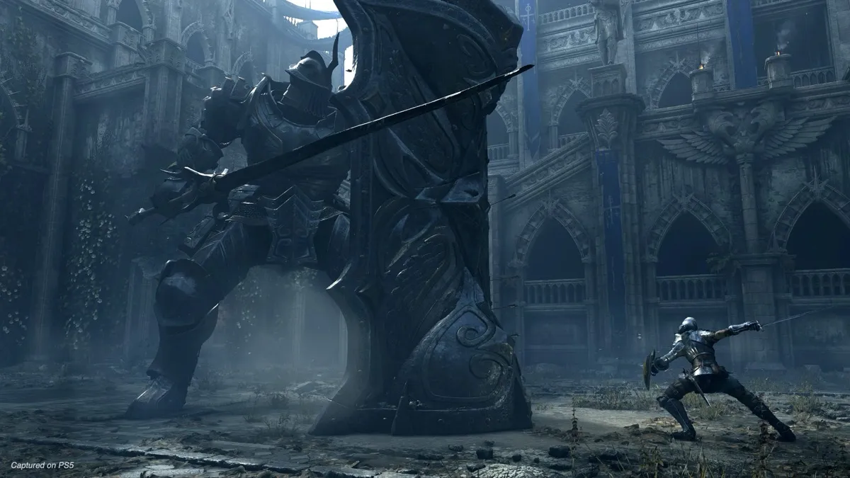 A lone knight stands against a towering armored giant in "Demon's Souls"