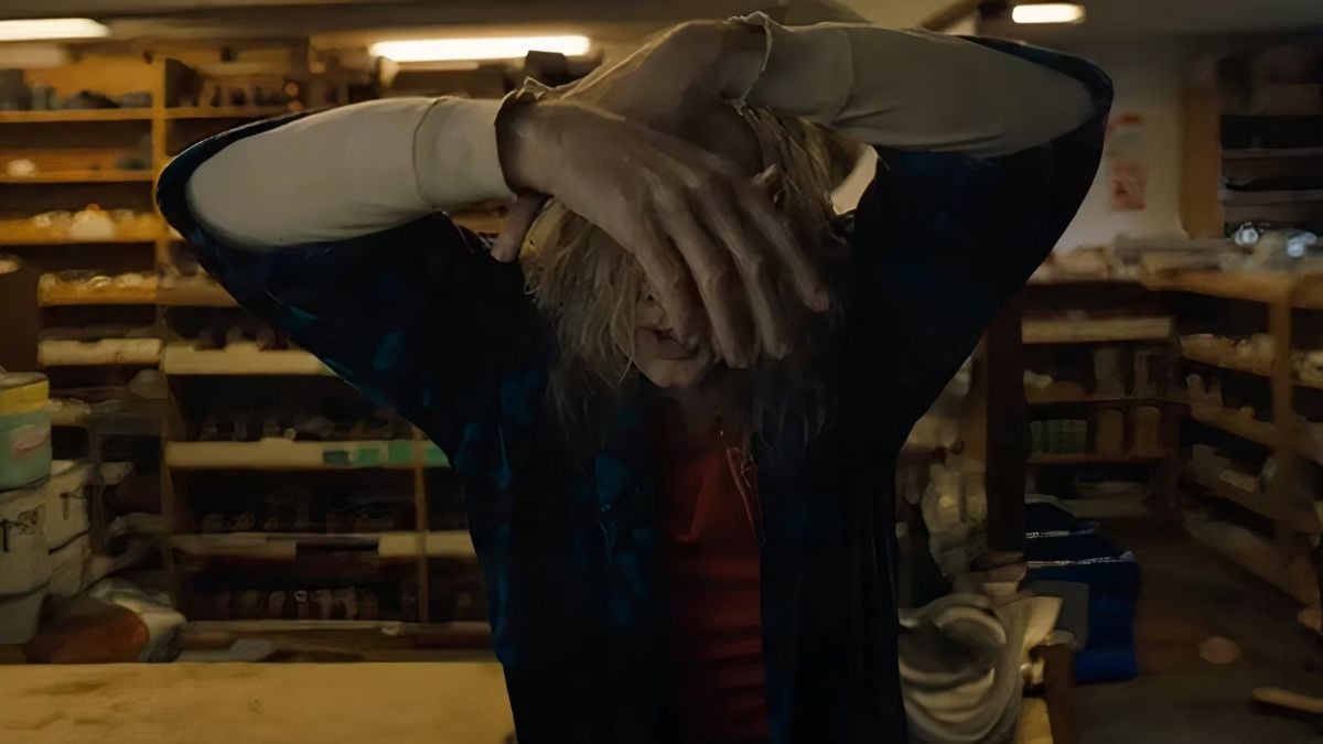 Nicolas Cage as Longlegs crosses his arms over his head and cover his face with his hands
